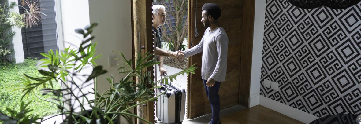 Man inside the house is shaking hands with someone who came to the front door