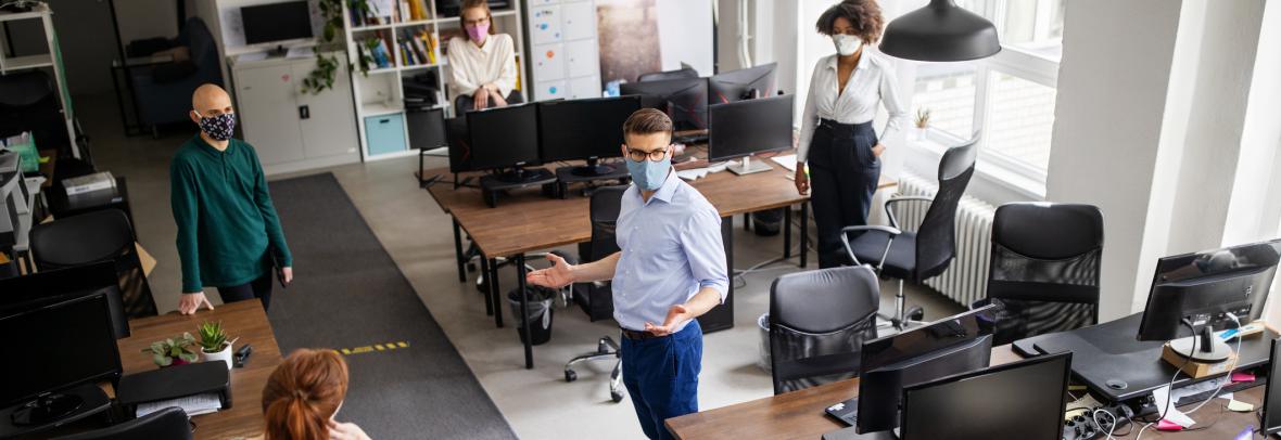 Co-workers social distancing and wearing masks in office