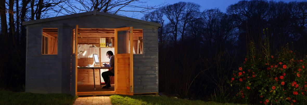 Many inside the door of a backyard shed using it as an office