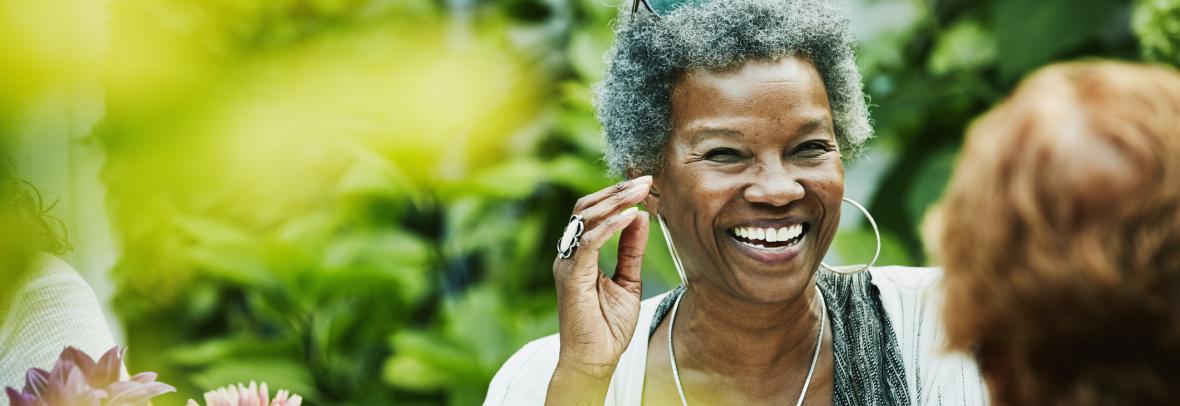 Older woman smiling while outdoors talking to another woman