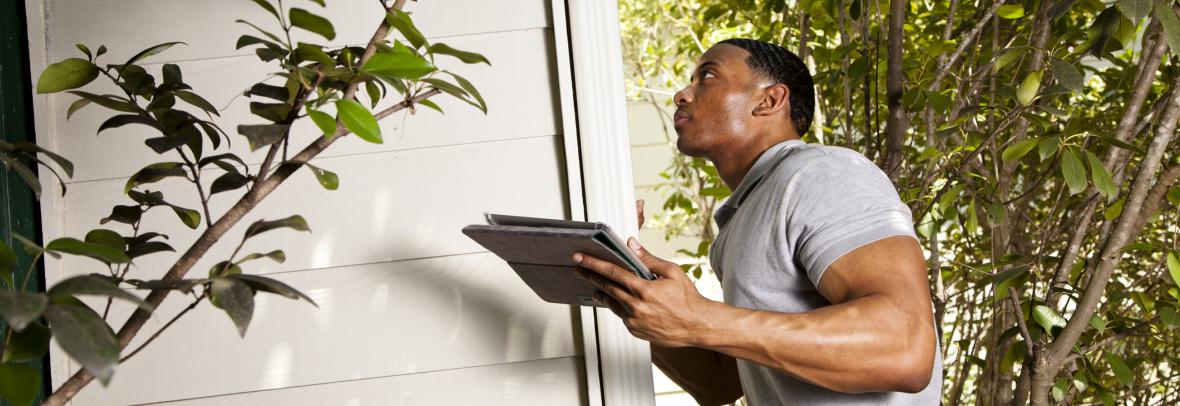Inspector with clipboard inspection a home's exterior