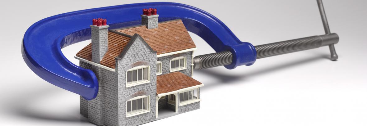 Small toy house with a C-clamp pushing against it