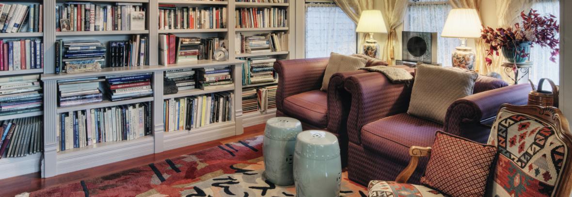 cozy living room with 3 armchairs and full bookcase wall