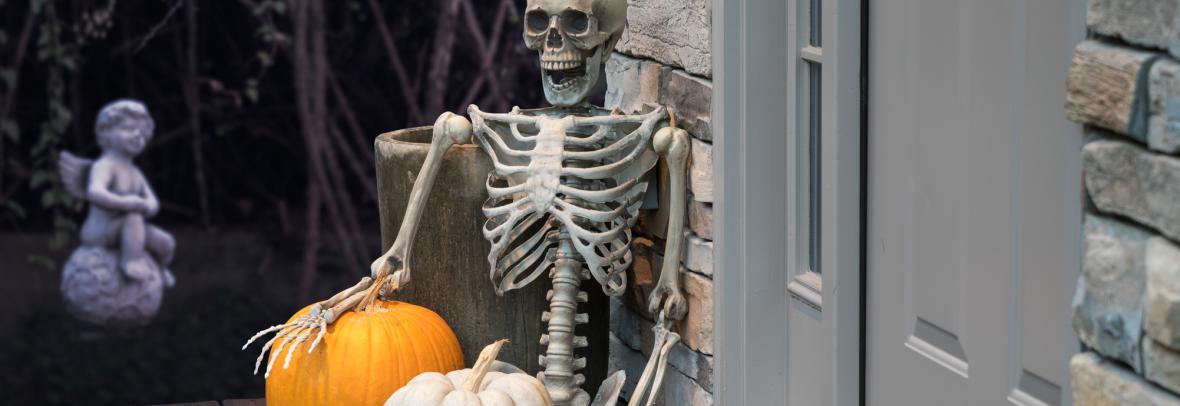 Skeleton and Halloween decorations on front porch by welcome mat