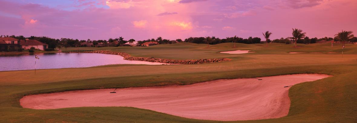 Golf course in red light of sunset with homes in the background