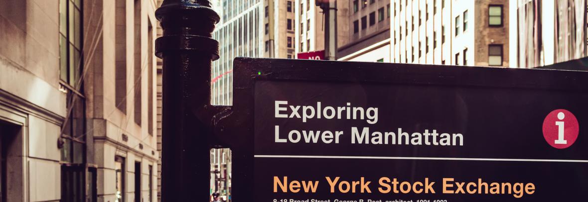 Wall Street photo with sign that says exploring lower Manhattan and New York Stock Exchange