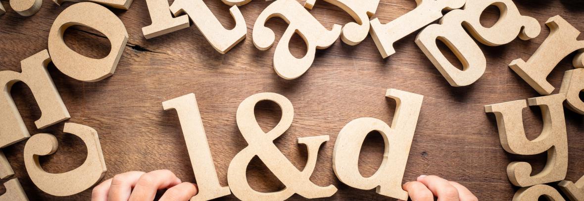 Closeup child's hand arrange wooden alphabets on the table as L&D abbreaviation, Learning and Development concept