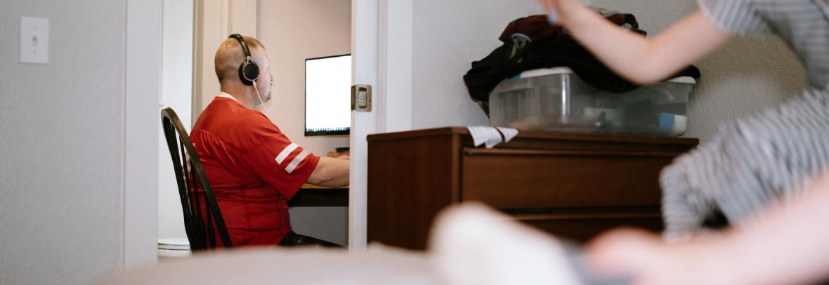 Many with headphones working inside a closet as a young child plays nearby