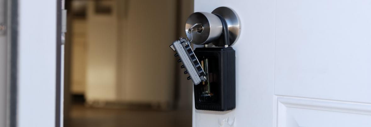 White door stands ajar with a lockbox over the outside knob