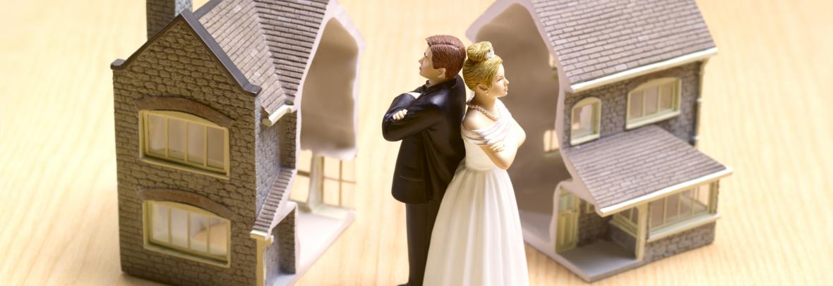 Cake topper couple back to back with two toy homes in background