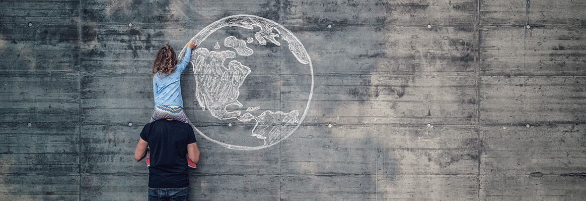 hoto of child drawing a globe in chalk on a grey wall