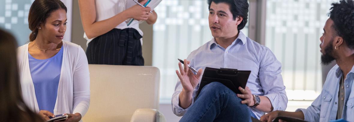 Mid adult male therapist gestures while discussing something with the people