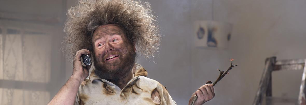 Home remodeler with blackened face and electrical wiring in one hand