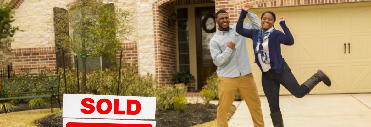 Black man and woman jump for joy after buying new home