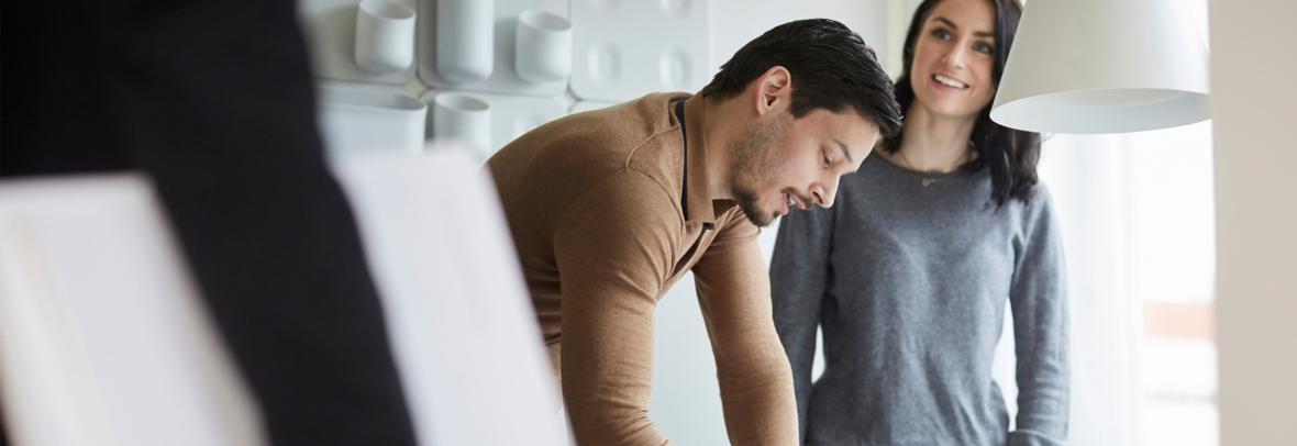 Woman looking at real estate agent while man signing documents at new home