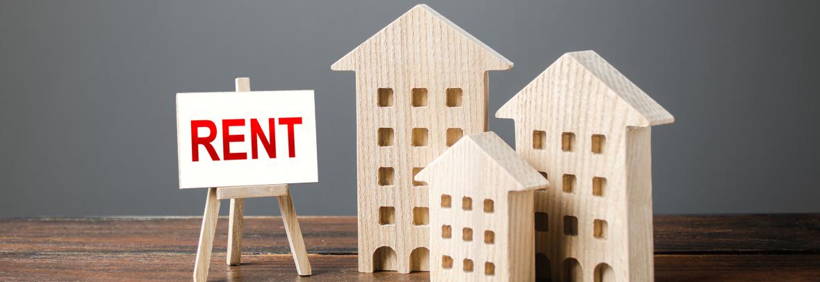 three wood block apartment buildings of different size with rent sign on easel