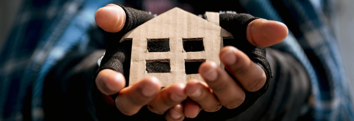 Homeless man holds cardboard cutout of a house