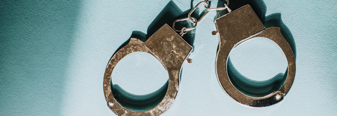 photo of metal handcuffs on a neutral blue background