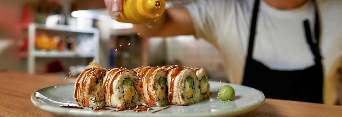 Gloved hand with condiment sprinkling drizzle over chicken cordon bleu