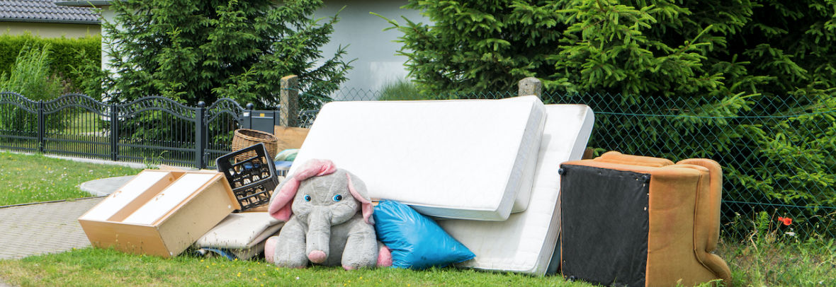 Mattresses, stuffed animal and chair sit in garbage pile near the street
