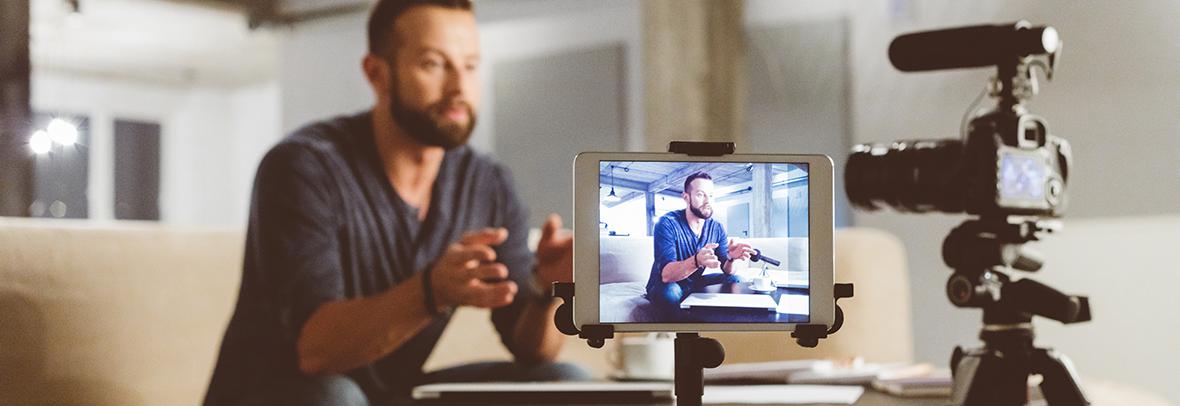 Photo of a man recording a video of himself in his office