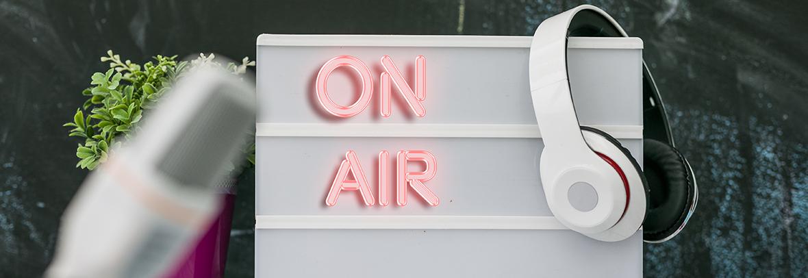 Photo of a sign that says On Air with headphones hanging on it.