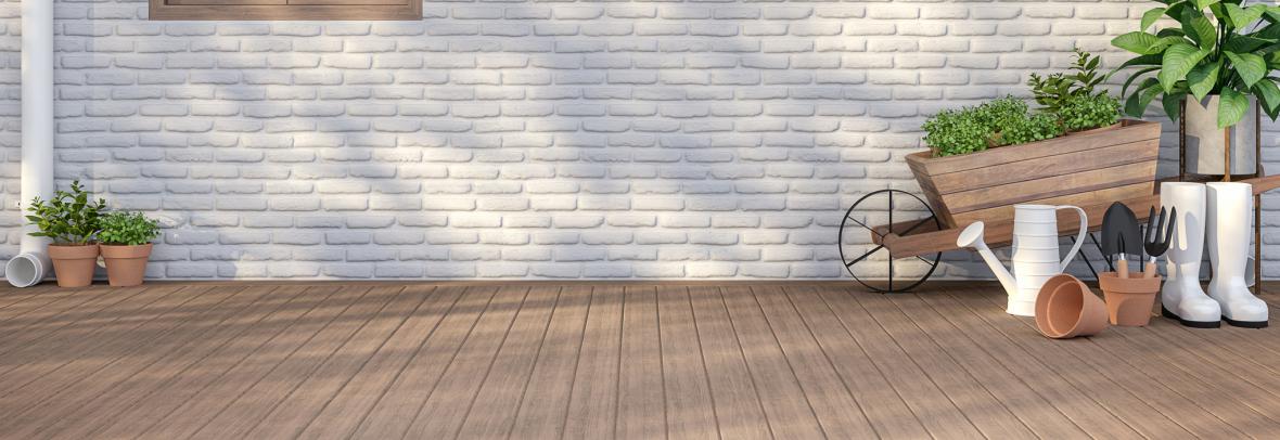 Home with white painted brick with a brown window and plants along the side