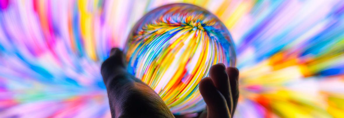 hand holding crystal ball with rainbow swirls all around it