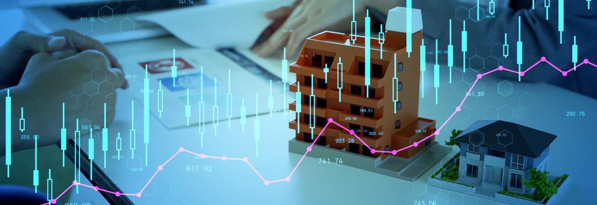 small model building and home on a desk with a laptop and digital investment overlay