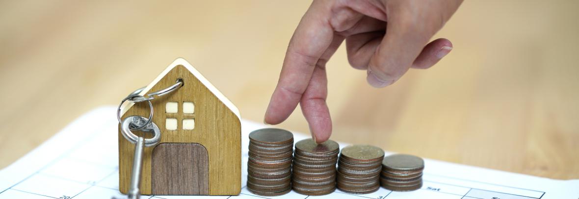 small wooden house with key, hand walking on stacks of coins, all on calendar page