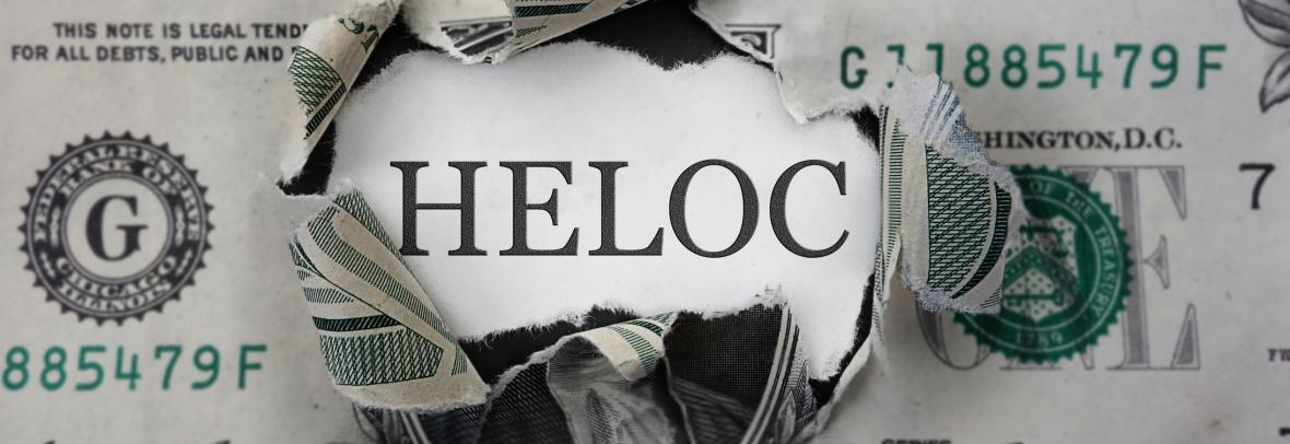 One dollar bill with a hole that says HELOC behind it