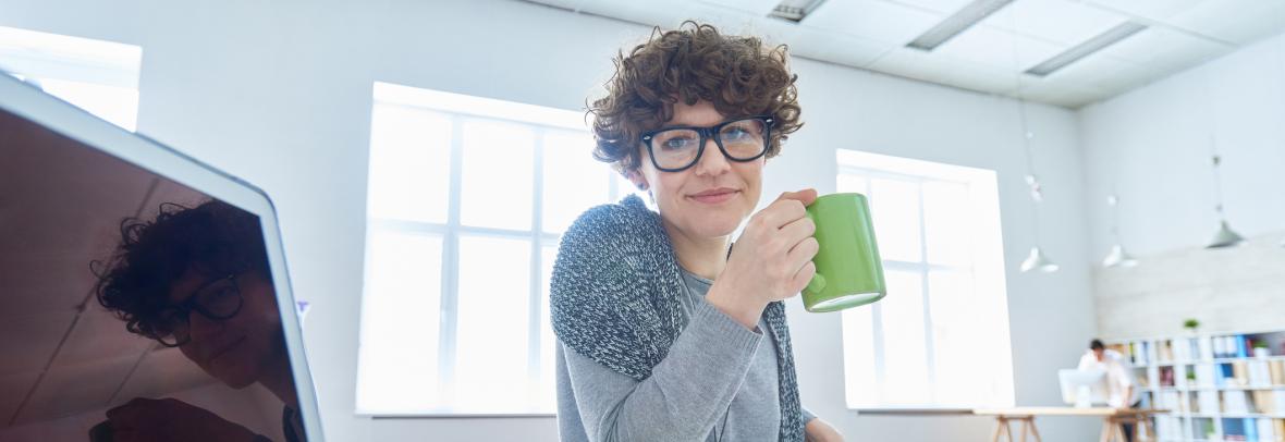 woman at computer desk holding coffee cup