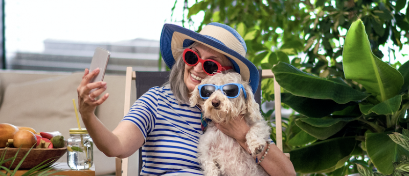 Woman and her dog wear sunglasses while taking a phone selfie