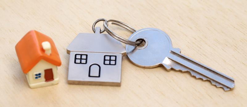 close up of small house beside metal house keychain and key