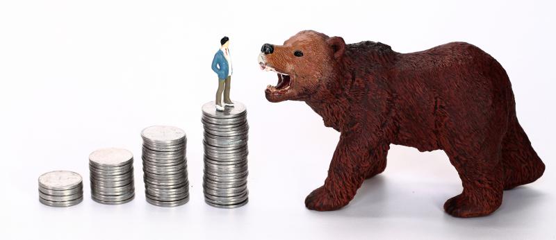 A toy bear growls at a man standing on top of a stack of coins