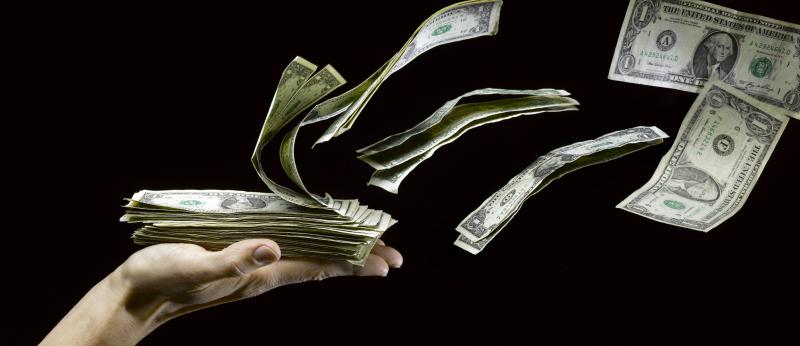 Money blows up and away from an open hand