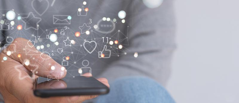 Photo of a person holding a phone with social media icons