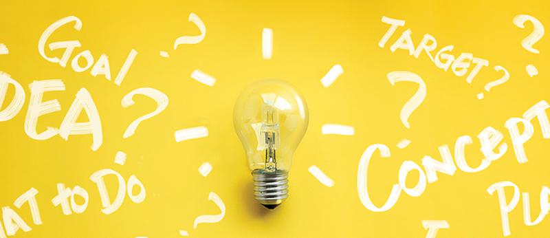Photo illustration of a light bulb with white writing around it on yellow background