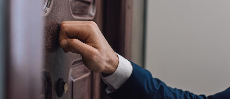 Photo of hand knocking on front door