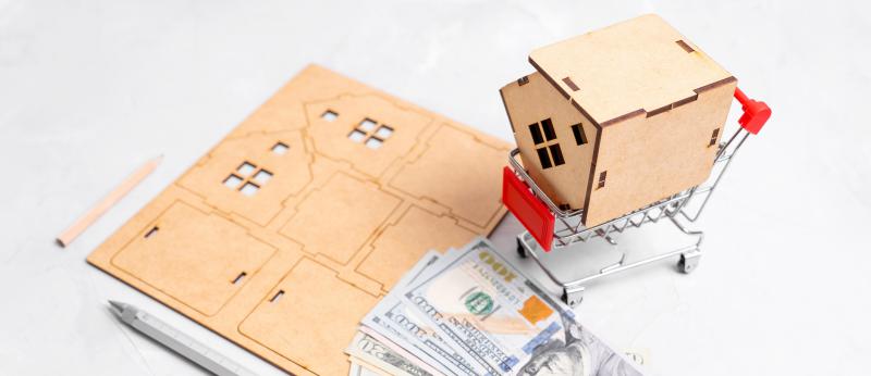 A cut-out, put-together toy home with money laying on top