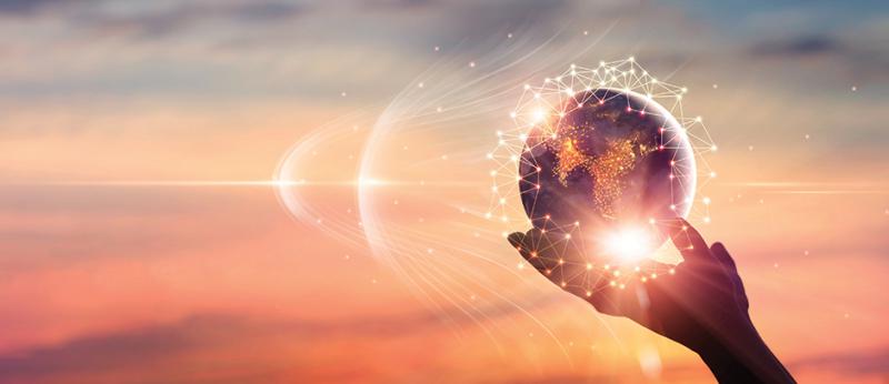 Photo of a hand holding a globe with rays of light emanating from it