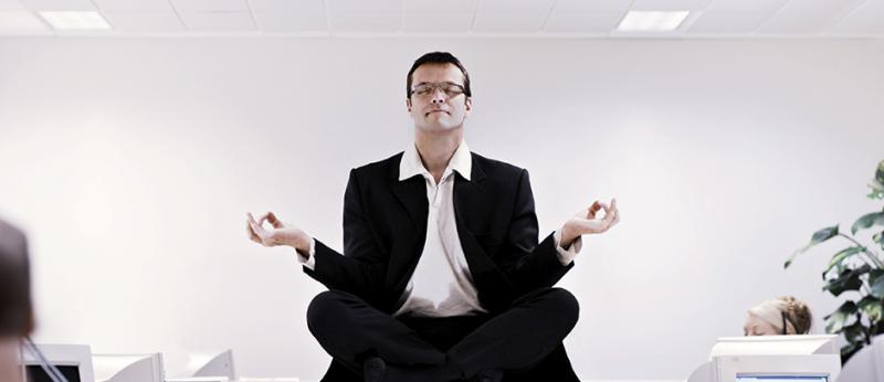 Photo of a business man sitting on a desk meditating