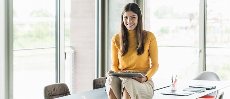 Photo of Millennial Realtor sitting on a desk using a tablet computer