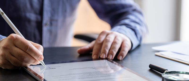 Photo of a man signing a contract on a tablet computer