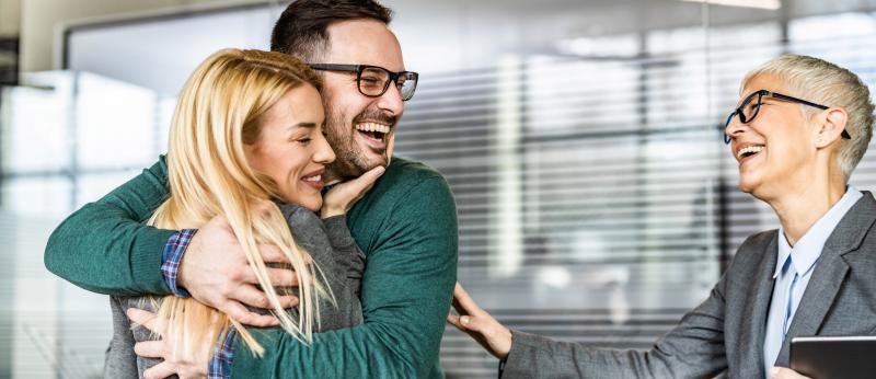 couple hugging and smiling while older woman looks on, smiling.