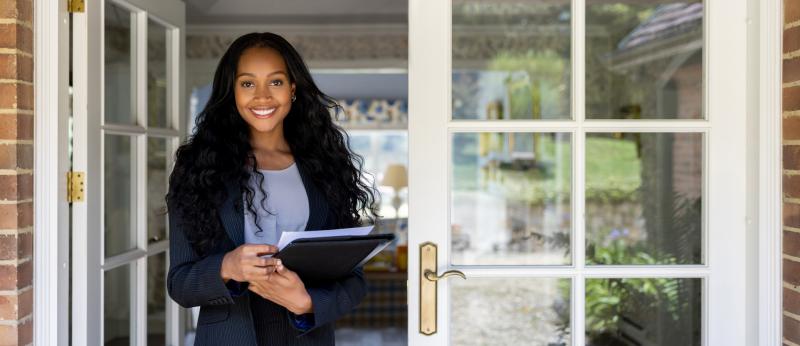 young female woman holding paperwork standing in open french door