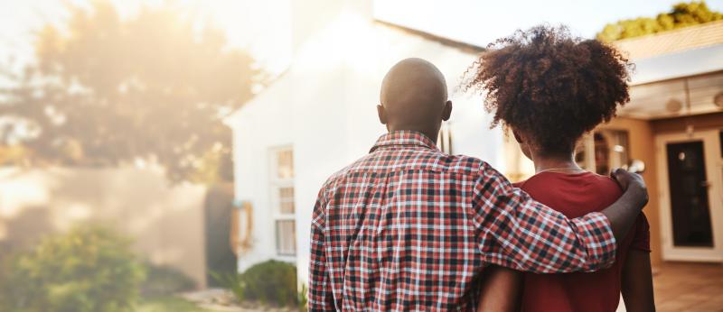 couple arm in arm looking at a house