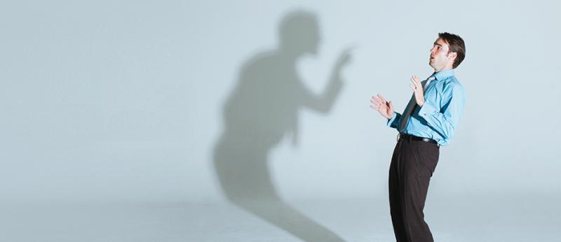 Photo of a man being criticized by a shadow of himself