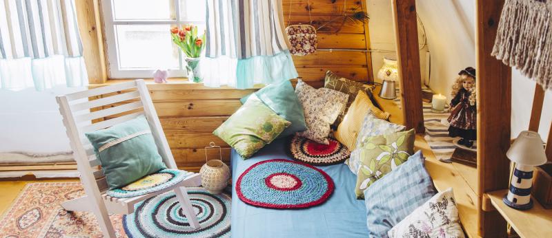 Maximalist maximalist home concept. Holiday home cabin bedroom with natural wooden board walls and ceiling and lot of different color details.