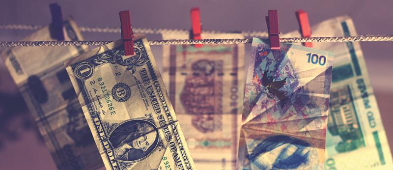 Image of US dollar bill and foreign dollars hanging on close line